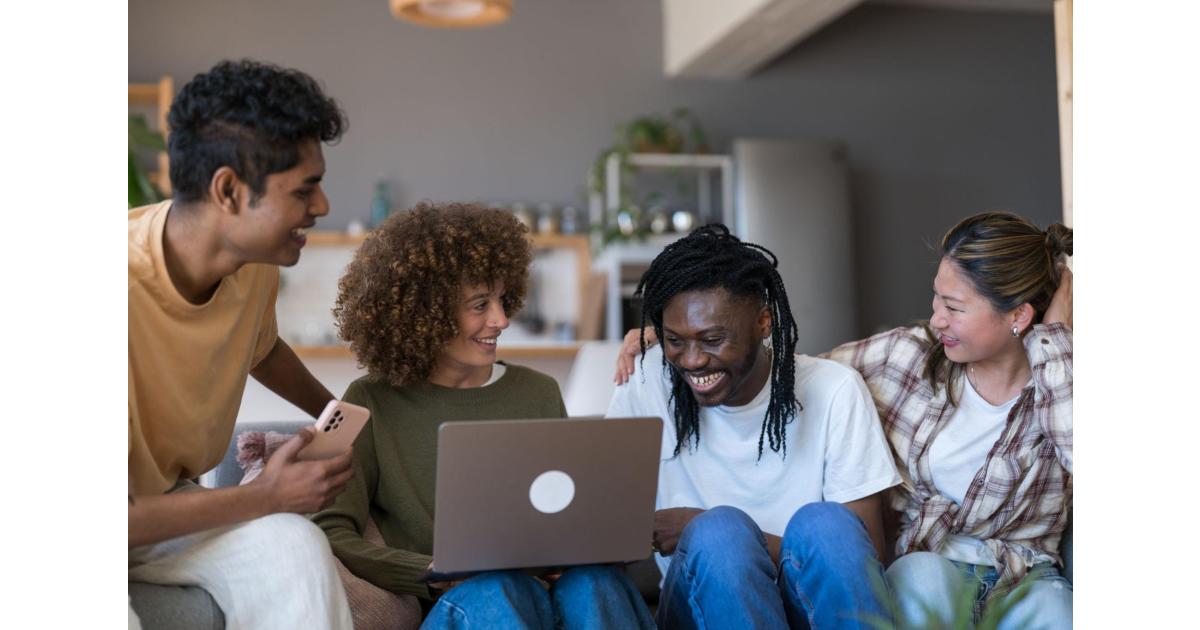 Jeune femme organisant un voyage en groupe sur ordinateur portable avec une plateforme de cagnotte en ligne, dans un appartement moderne en Suisse.