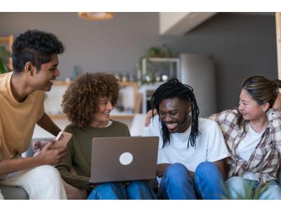 Jeune femme organisant un voyage en groupe sur ordinateur portable avec une plateforme de cagnotte en ligne, dans un appartement moderne en Suisse.