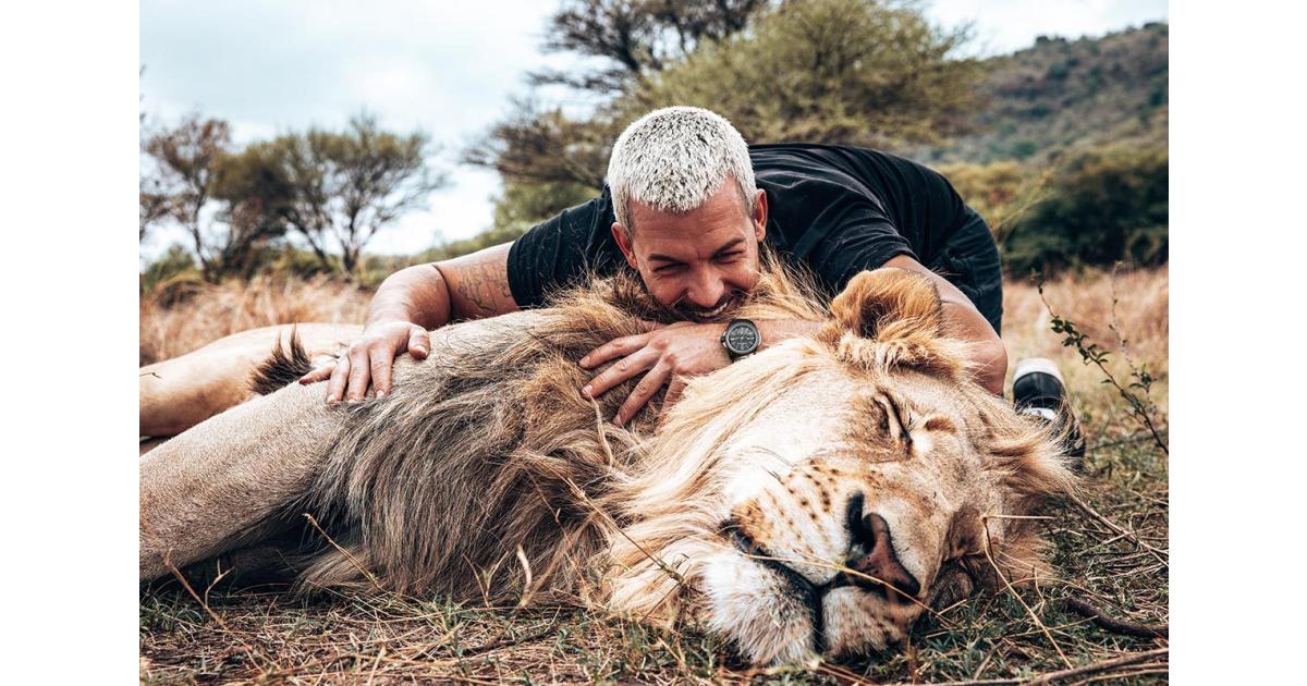 Dean Schneider interacting with a lion at Hakuna Mipaka wildlife sanctuary in South Africa, showcasing his work in animal rescue and conservation.