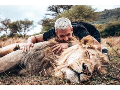Dean Schneider interacting with a lion at Hakuna Mipaka wildlife sanctuary in South Africa, showcasing his work in animal rescue and conservation.